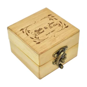 Caja para anillo tipo maletín en madera triplex de pino en crudo de 9x9x6 cm con cierre y manija metálica sobre fondo blanco.