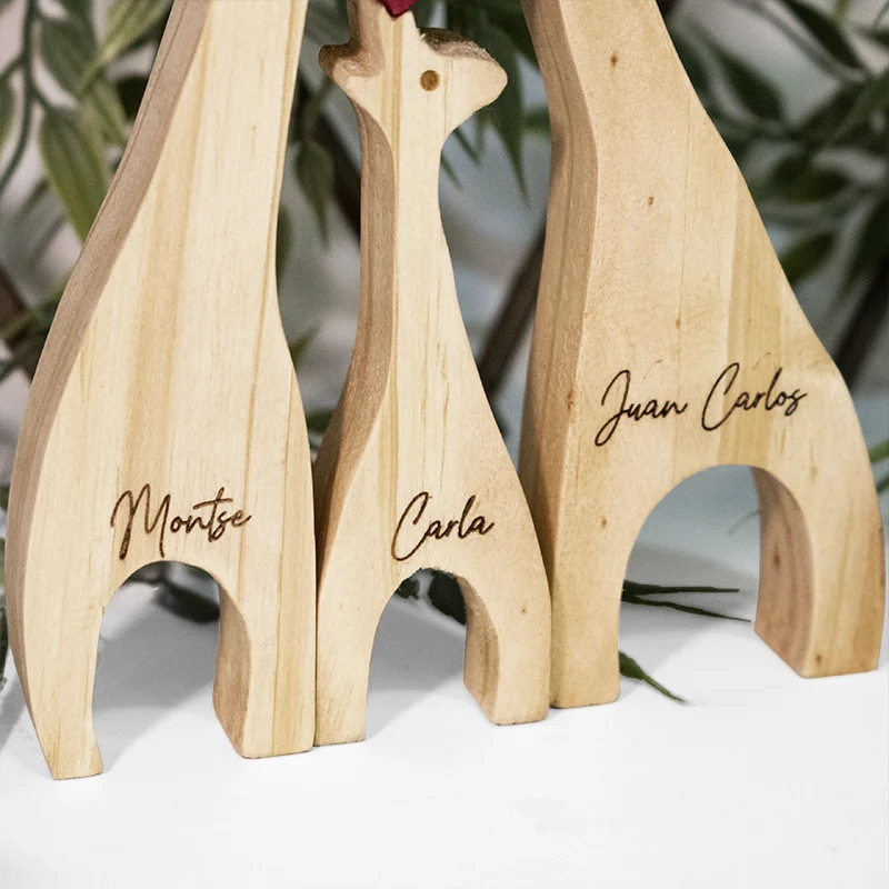 Escultura Familia 3 Jirafas en Madera Acercamiento al grabado láser de nombres y fechas sobre la superficie de madera de pino.
