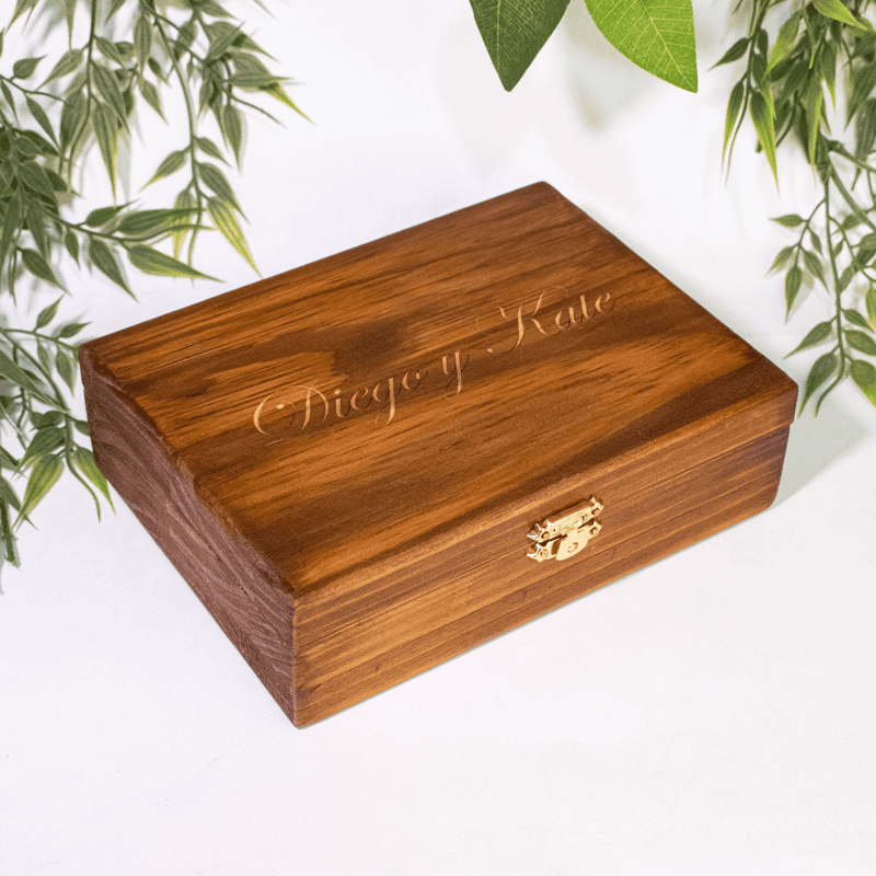 Las Cajas de Compromiso están hechas de madera de alta calidad, con un diseño elegante y resistente. Cada caja es fabricada a mano bajo pedido, lo que permite personalizarla con grabados láser de iniciales, fechas o mensajes especiales. Con dimensiones que varían según el diseño, estas cajas son perfectas para guardar y presentar el anillo de compromiso en un momento tan importante. Además de su uso práctico, tienen un valor simbólico y decorativo, convirtiéndose en un recuerdo perdurable que podrá ser reutilizado para almacenar objetos especiales. Su fabricación bajo pedido asegura que cada caja sea única y especial, reflejando la personalidad y el estilo de la pareja.