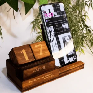 Calendario de Madera y Soporte Celular Calendario de Madera y Soporte para Celular, fabricado en madera natural con dimensiones de 12 cm de alto, 19 cm de largo y 8 cm de ancho. Incluye un calendario perpetuo con bloques grabados y un soporte integrado para celular. Personalizable con grabado láser, ideal para uso decorativo y funcional.