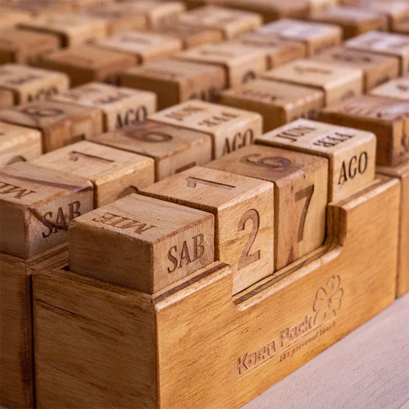 caledarios-cubos-madera-personalizado-detalle Un emocionante juego de mesa de fútbol realizado en madera. El tablero está dividido en dos campos, cada uno con el logo de un equipo de fútbol reconocido. En cada campo, hay una serie de agujeros donde se colocan pequeñas fichas que representan los jugadores. El objetivo del juego es embocar las fichas en la portería contraria utilizando un mecanismo de lanzamiento. El juego está diseñado para dos jugadores y fomenta la competencia amistosa y la diversión.